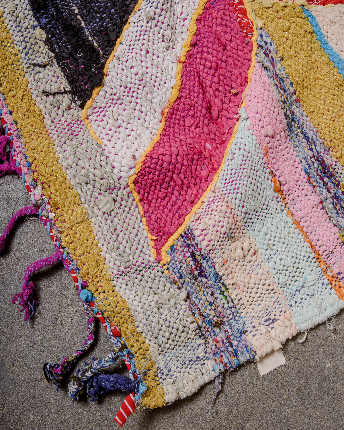 Corner of vintage kelim rug with cotton tassels in different colour combinations.